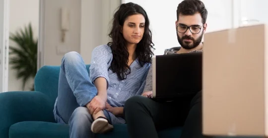 Richtig abgesichert im Eigenheim: Junges Paar bei Online-Beratung.