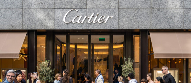 Menschen warten vor einem Cartier-Geschäft in einer Schlange, während Passanten vorbeigehen.