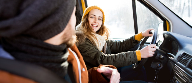 Beautiful young couple on a trip in winter, close up of girl driving.