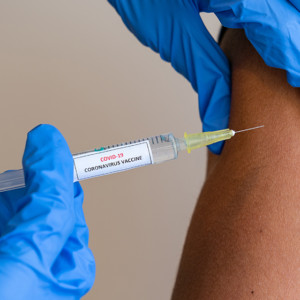 This picture depicts a young female clinician using a syringe to inject a concept COVD-19 liquid vaccine into a young girl patient during the Phase 3 vaccination human trials.
