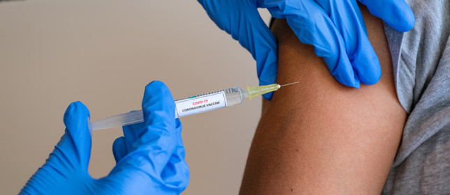 This picture depicts a young female clinician using a syringe to inject a concept COVD-19 liquid vaccine into a young girl patient during the Phase 3 vaccination human trials.