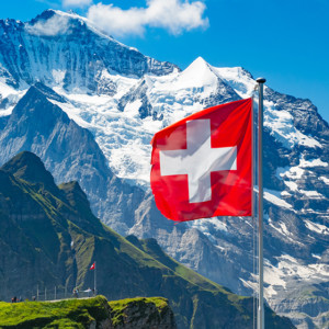 Swiss flag waving and tourists admire the peaks of Jungfrau mountain on a Mannlichen viewpoint, Bernese Oberland Switzerland