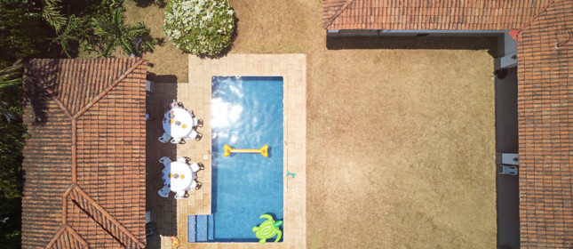 house backyard with swimming pool above drone view on sunny day
